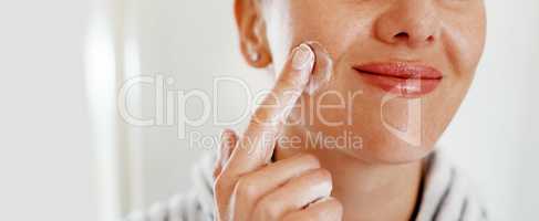 Never allow your skin to stay dry. Cropped shot of an unrecognizable woman looking cheerful while applying moisturizer on her at home.