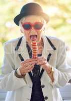 Her inner child is craving ice-cream. Portrait of a fun-loving senior woman eating an ice-cream outside.