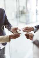 Building on their collective vision. Closeup shot of a group of unrecognizable businesspeople joining puzzle pieces together in an office.