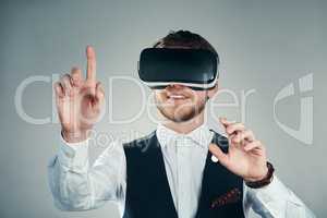 Immersed in a virtual business environment. Studio shot of a handsome young businessman using a vr headset against a grey background.