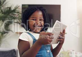 This has all the entertainment I need. Portrait of an adorable little girl having fun while using digital a tablet at home.