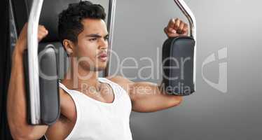 Feeling good about my body. A fitness shot of an athletic young man using an exercise machine.