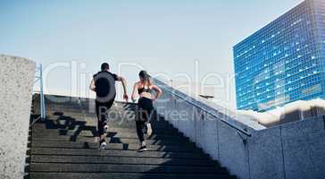 Do whatever gets your blood flowing. Rearview shot of a young man and woman running up stairs together in the city.