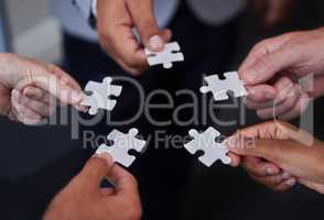 Always welcome help thats offered. Shot of a group of businesspeople putting together puzzle pieces.