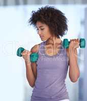 Toning her biceps. Cropped shot of an attractive young woman working out with dumbbells.