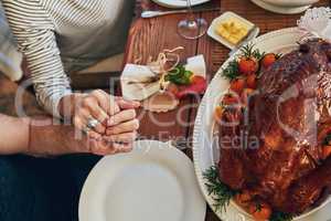 Find reasons to give thanks. High angle shot of a couple holding hands at the dining table.