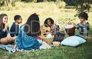 What song should we play next. Shot of a group of teenagers playing musical instruments in nature at summer camp.