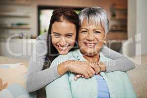 All grown up, but still her mothers daughter. Cropped portrat of a young woman hugging her mature mother in the living room.