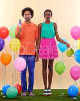 Feeling a bit out of place.... An awkward african couple surround by colorful balloons while holding hands.