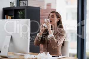 Too many sneezes are interrupting her way towards success. Shot of a young businesswoman suffering with allergies at work.