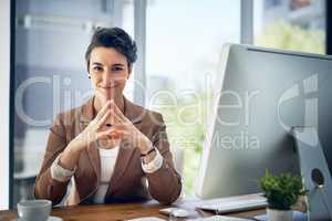 Shes got big entrepreneurial ambitions. Portrait of a businesswoman working at her desk in an office.