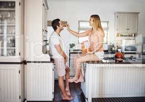True love is sharing your food. Shot of a young woman feeding her boyfriend a snack in the kitchen.