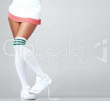 Showing my shyness through my feet. Close up of womans legs in a skirt and long socks with trainers on with copyspace.