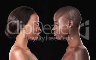 Perfect profiles. Two beautiful african women standing face to face against a black background.