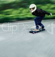 Thrilled by speed. Shot of a man skateboarding down a lane at high speed on his board.