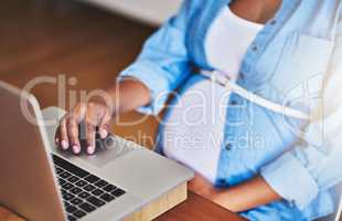 Researching online tips for a growing pregnancy. Cropped shot of a pregnant woman using a laptop while working from home.