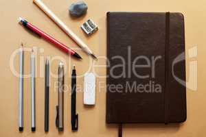 Give your inner artist room to play. Studio shot of a sketchpad and other various artistic against a brown background.