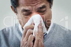 Allergy season is here. Shot of a mature man blowing his nose.