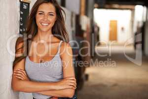 One hot equestrian. A young woman smiling in a stable.