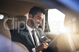 Finding success while on the road. Cropped shot of a handsome young businessman using a tablet while on his morning commute to work.