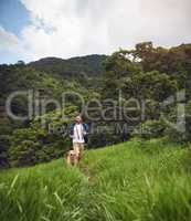 Race you to the top. Full length shot of a handsome young man running with his golden retriever during a hike.