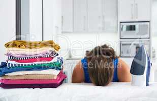 Shes run out of steam. Shot of a young woman with her head down on an ironing board.