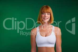 Commit to be fit. Cropped portrait of an attractive young sportswoman standing alone against a green background in the studio.