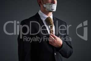 Nothing kills business like dishonesty. Studio shot of a businessman with rope around his neck and money taped over his mouth against a gray background.