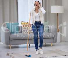 Make cleaning your home fun. Shot of a young woman listening to music while sweeping her floor.