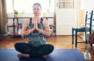 Focusing on my breath. Cropped shot of an attractive young woman sitting on a yoga mat and meditating alone in her home.