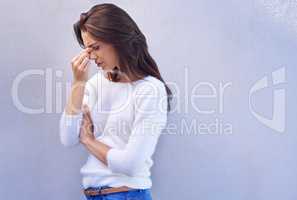 Remember to inhale confidence and exhale doubt. Shot of an attractive young woman with a headache standing against a gray background.