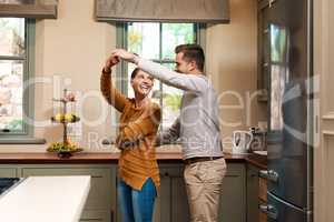 Shes forever his princess. Shot of an affectionate young couple dancing together in their kitchen at home.