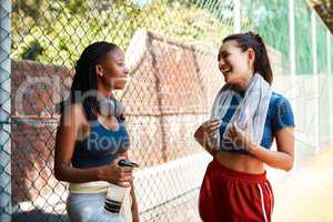 It helps to have a buddy to keep you motivated. Shot of two sporty young women chatting to each other against a fence outdoors.