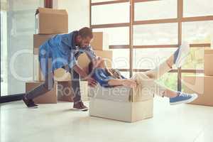 New beginnings.... Shot of a happy young couple having fun while moving into their new home.