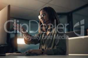 Giving clear instructions for the solutions. Shot of a call centre agent working in an office at night.