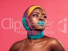 Eye-catching isnt she. Studio shot of a beautiful young woman wearing a head wrap and make up against a pink background.
