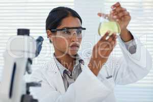 Focused on solving medical mysteries. Cropped shot of a young female scientist conducting an experiment in a lab.