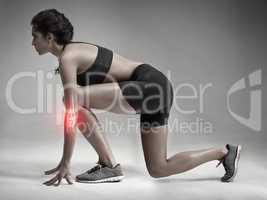 Ready set go. Studio shot of an attractive young woman getting ready to sprint while CGI shows her injured elbow.