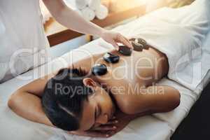 Healing with the power of heat. Shot of a young woman getting a hot stone massage at a spa.