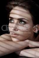 Contemplating beauty. A young woman with flawless skin and dark hair looking away against a dark background.