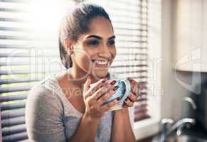 Coffee is where good vibes come from. Cropped shot of a beautiful young woman,enjoying a cup of coffee at home.