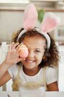 Showing off my art. Shot of a little girl covering her eye with a painted Easter egg.