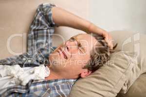 Dealing with a bad breakup. A young man crying while lying on the sofa with tissues.