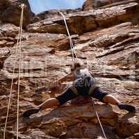 Shes challenging herself on this climb. Shot of a young female climber traversing a rock face.