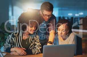 Making a few final changes. Cropped shot of a group of young people working late in the office.