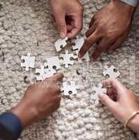 Pulling together to solve a problem. Cropped shot of a group of people fitting puzzle pieces together.