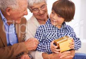Grandparents always spoil their grandkids. A young boy getting a gift from his grandparents.