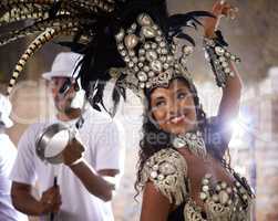 Turning beats into heat. Shot of a beautiful samba dancer performing in a carnival with her band.