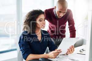 I was just reading over this paperwork.... Cropped shot of a male supervisor helping an attractive young businesswoman while working in their office.