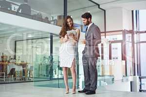 Business operations made easier and efficient with modern technology. Shot of a young businessman and businesswoman using a digital tablet together in an office.